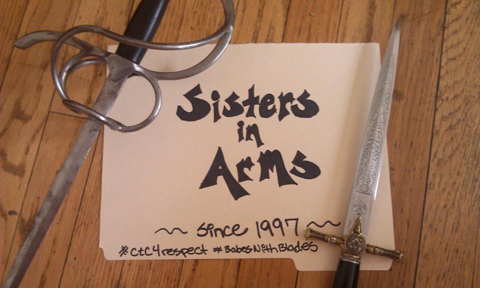 Sisters in Arms since 1997 written on a piece of paper, surrounded by a rapier and dagger