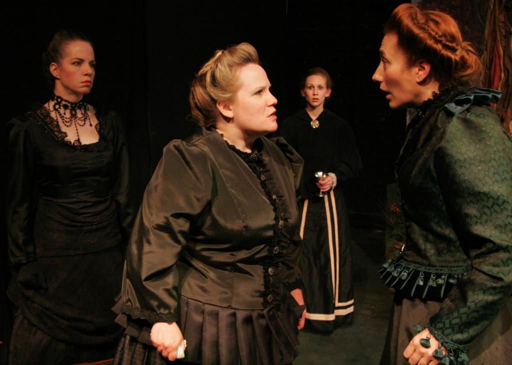 In VIctorian mourning clothes, two women argue while two others watch.