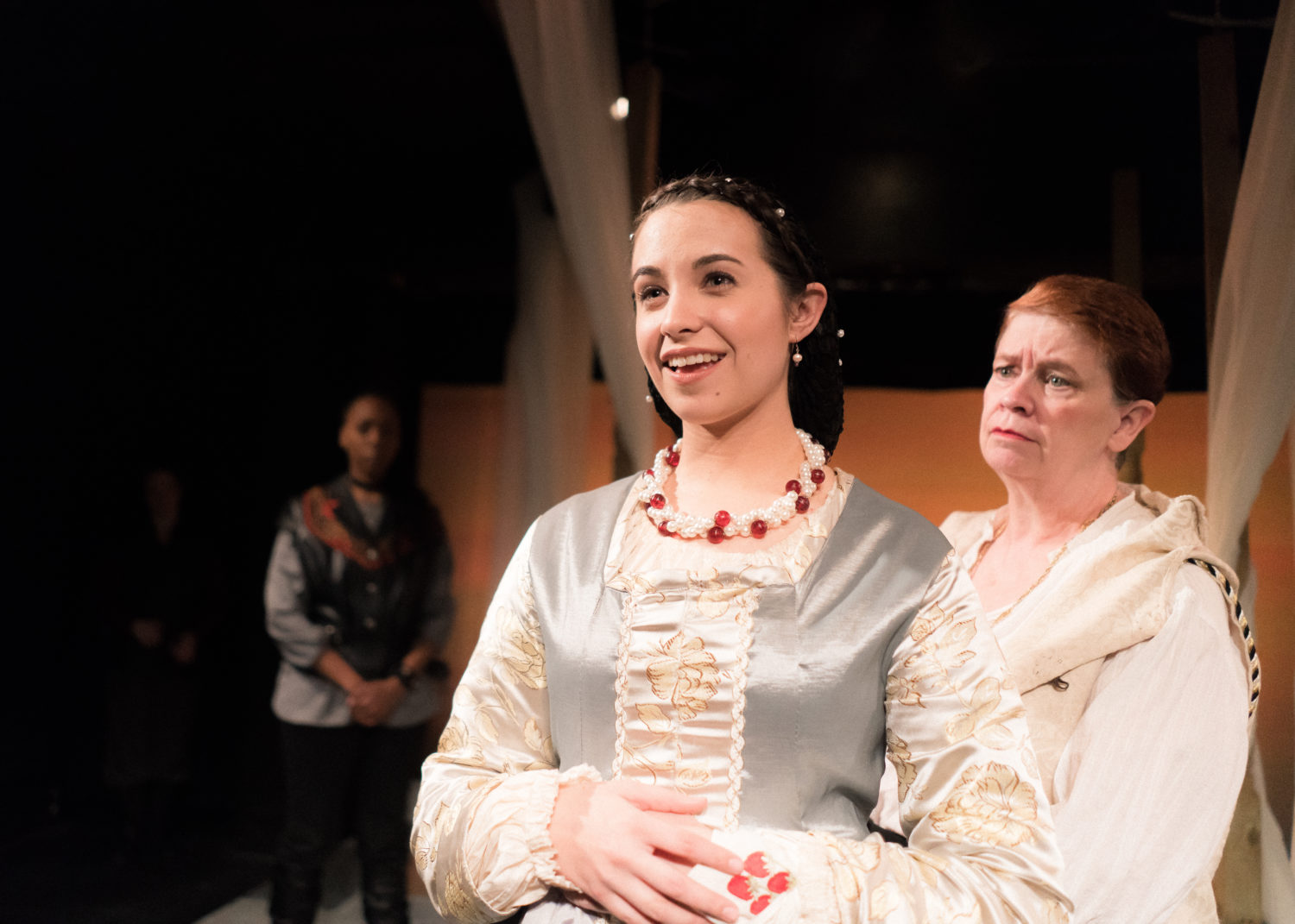 Desdemona stands before her elder and husband, stroking the handkerchief with strawberries sewn on it