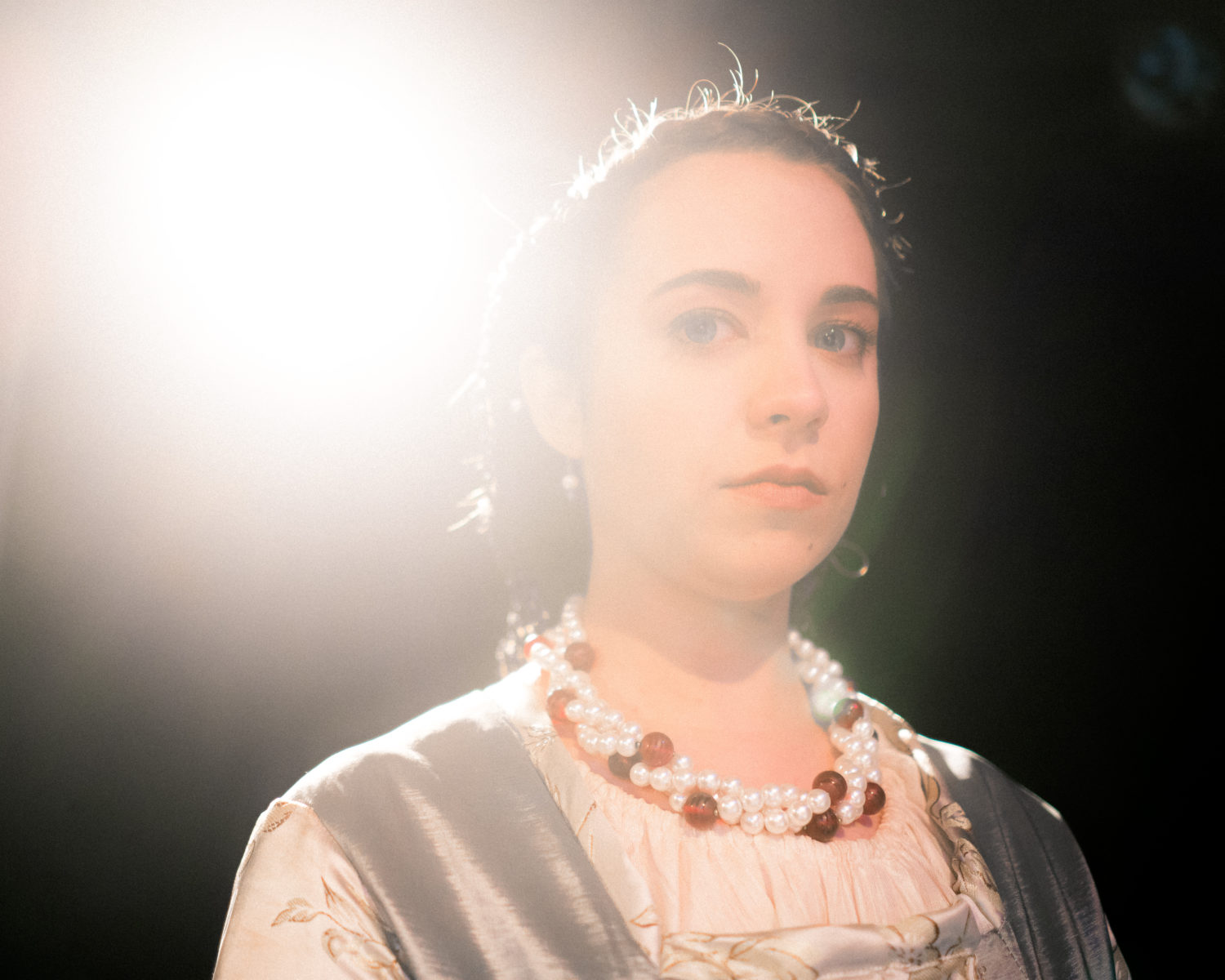 Desdemona stands under a light