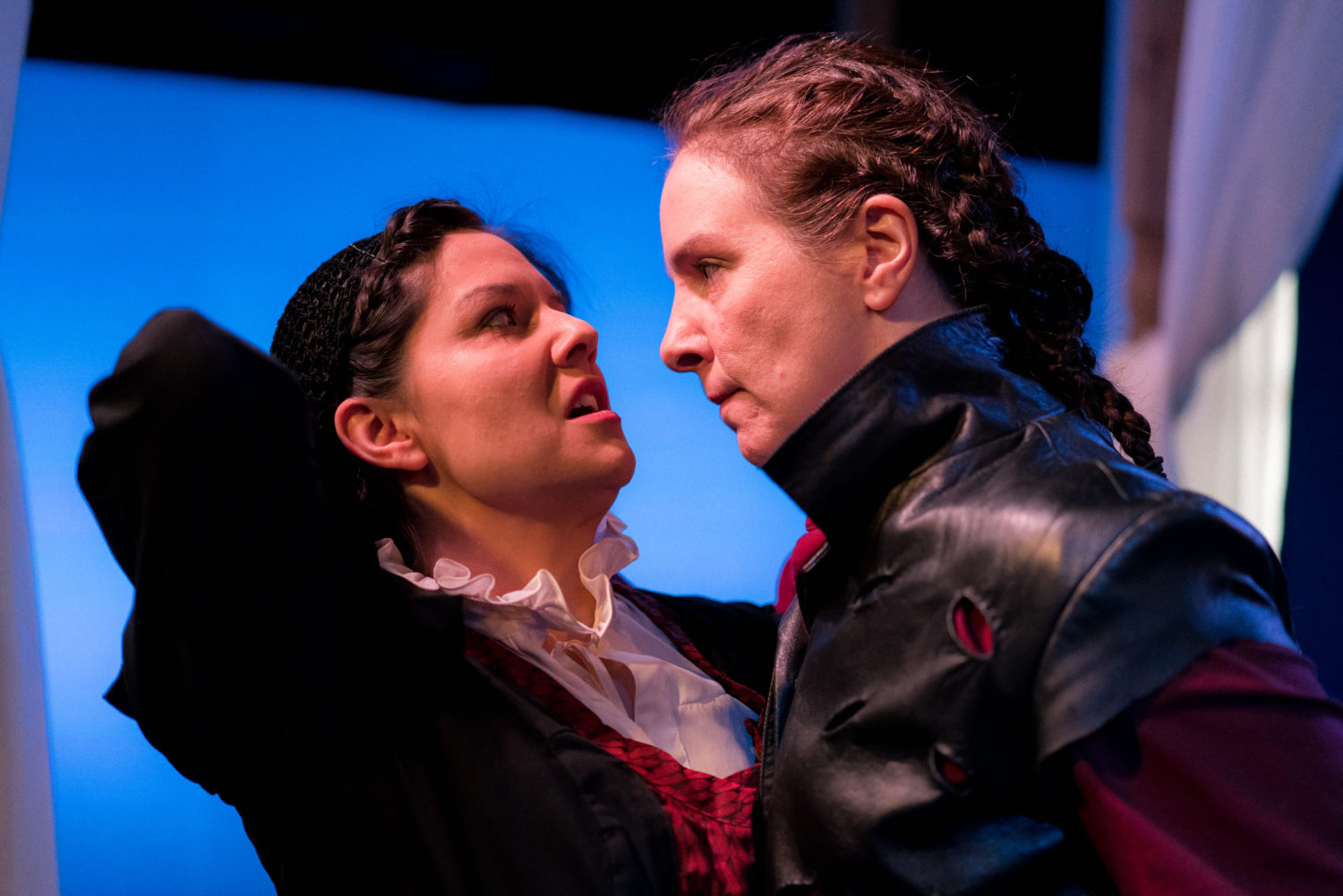 Iago menacingly gets in Aemelia's face while gripping her from behind