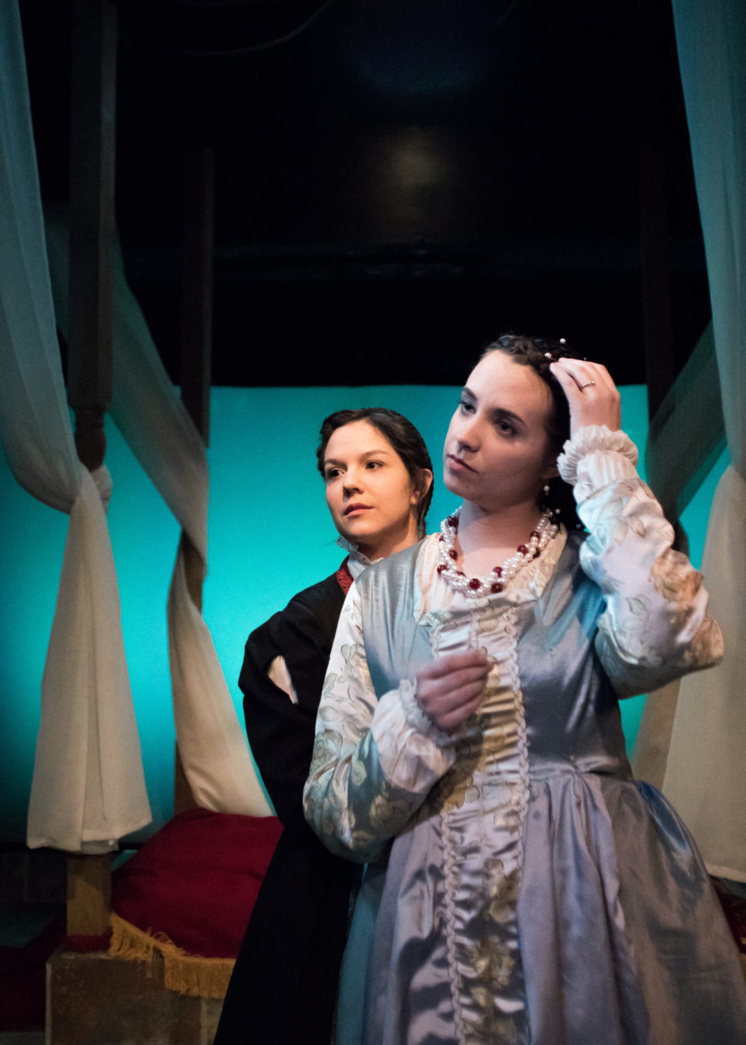 Aemelia stands behind Desdemona who is preparing for bed