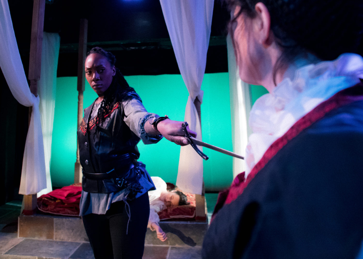 Othello holds a dagger pointed at Aemelia; Desdemona lies dead on the bed behind Othello